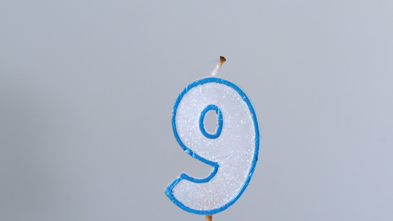 nueve velas de cumpleaños parpadeando y apagándose sobre un fondo azul