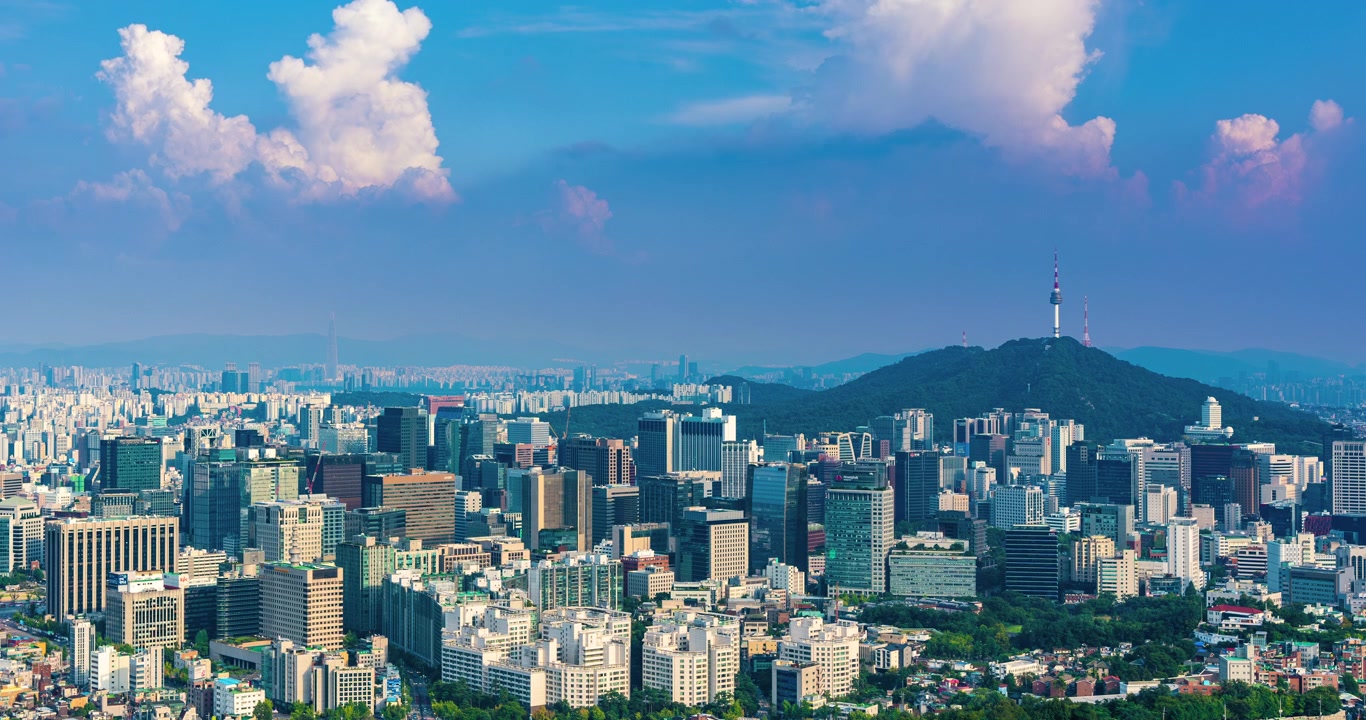Quang cảnh Tháp Namsan N Seoul từ núi Inwangsan vào một ngày hè. Tua nhanh thời gian những đám mây di chuyển trên đường chân trời thành phố Seoul với các tòa nhà chọc trời và văn phòng khu trung tâm thương mại.