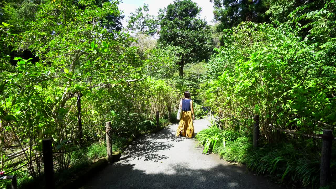 una mujer camina por uno de los senderos en un templo en kamakura, al sur de tokio