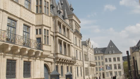 Pan-from-monumental-building-to-people-walking-over-street-in-downtown-luxembourg