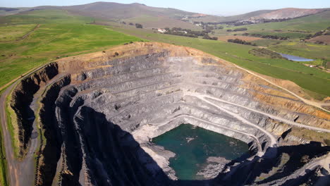 open-cast quarry mine cut into lush landscape for aggregate products, aerial