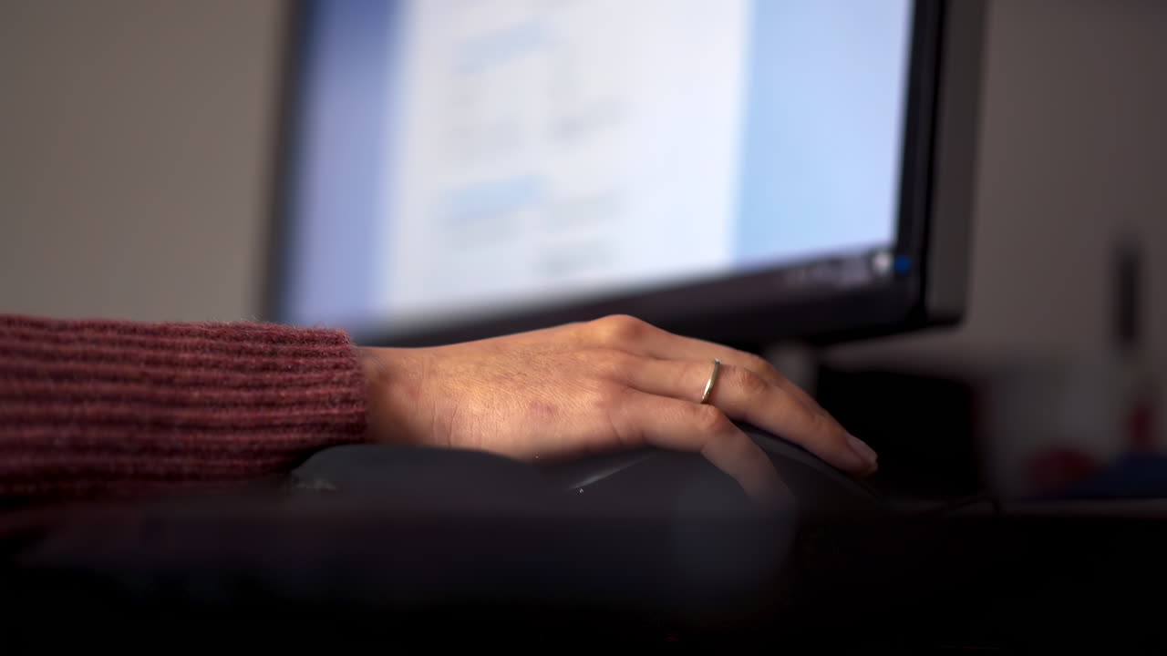 A hand is seen navigating a computer mouse while a website is displayed on the screen, showcasing a comfortable and focused atmosphere in a home office