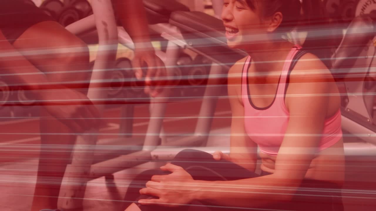 Female client holding knee on bench, male trainer approaching, kneeling, examining, guiding rehab