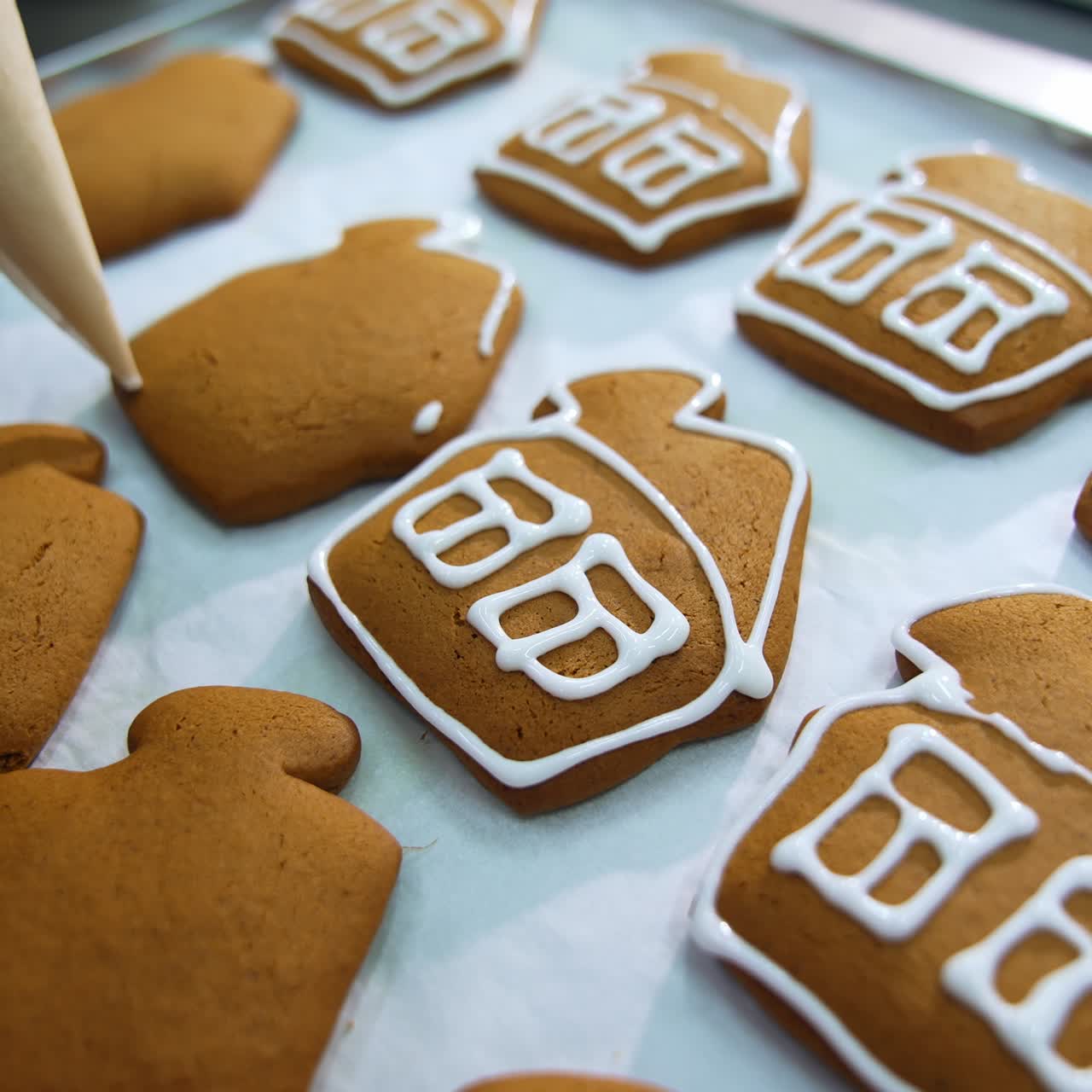 Decorazione artigianale di biscotti in una pasticceria. Applicazione di glassa bianca su splendide casette di pan di zenzero. Primo piano