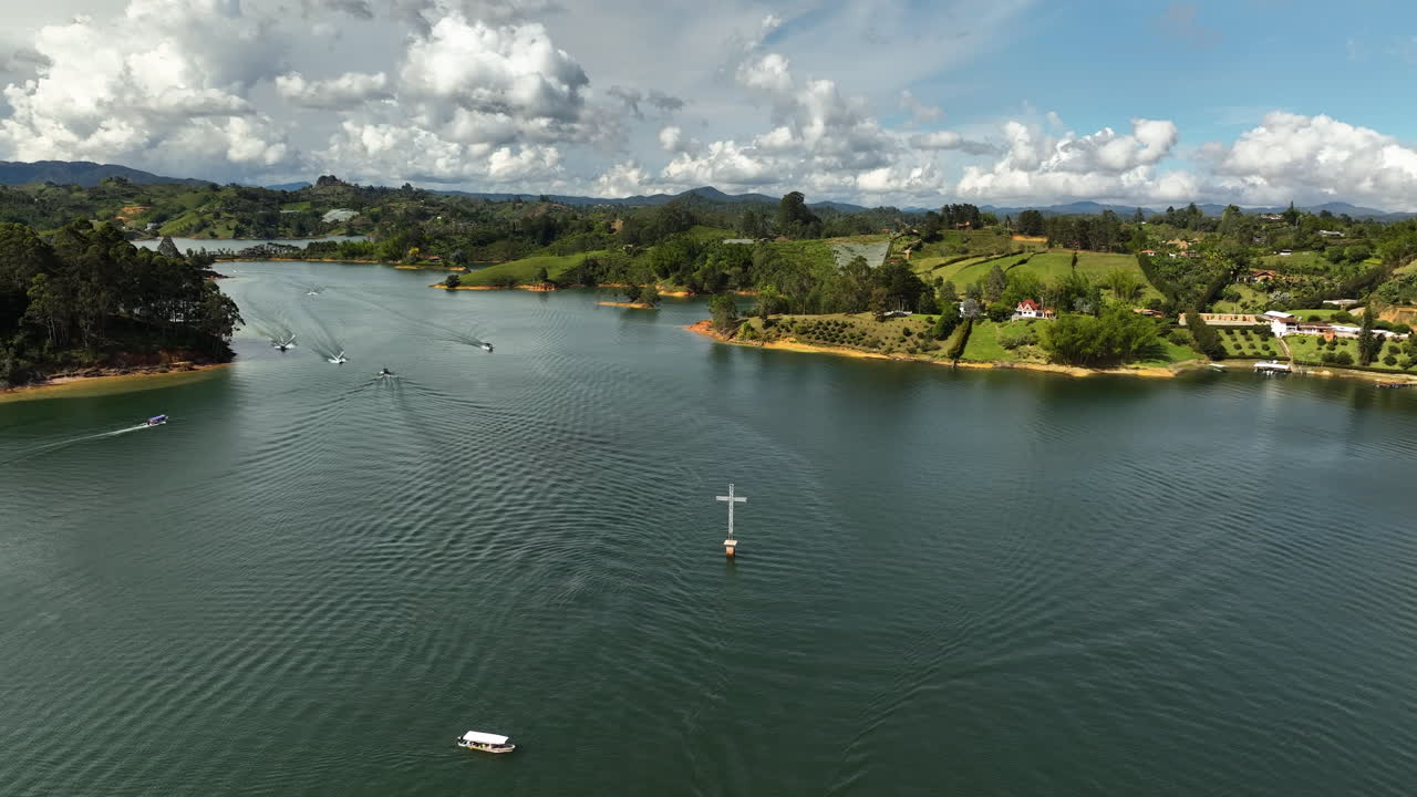 Drone shot in front of a cross on the Pe&ntilde;ol-Guatap&eacute; Reservoir in sunny Colombia