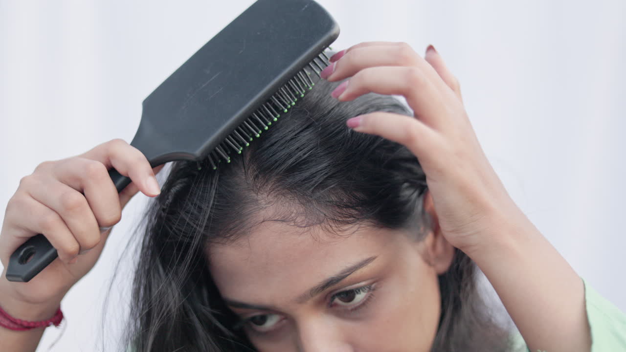 Close up shot of a young lady brushing her hair with comb, hair care concept.