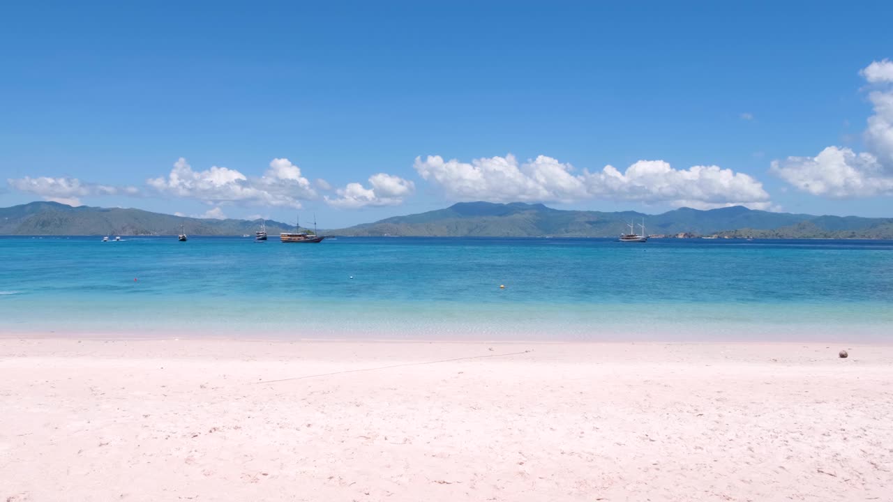 идиллический вид на океан с бирюзовой водой, туристические лодки и тропический остров с розового пляжа на острове комодо во флоресе, индонезия