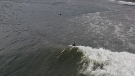 Vista-Aérea-De-Seguimiento:-Surfista-Montando-Olas-De-Regreso-A-La-Playa