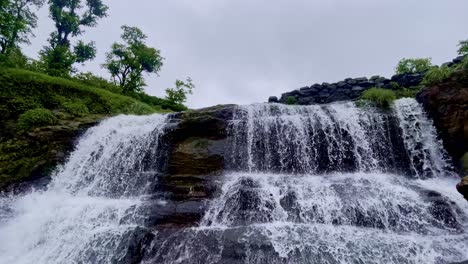 majestic waterfalls in bhandardara, maharashtra, india, cascade amid a lush green forest, captured in a breathtaking tilt-up view. surrounded by mist and monsoon bliss