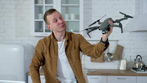 young man showing drone. man playing with professional drone in room