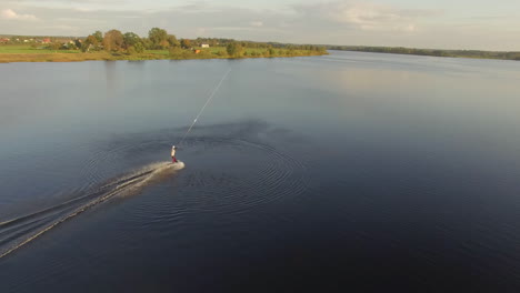 Vista-Aérea-Que-Muestra-Un-Dron-Tirando-De-Un-Wakeboarder-Navegando-Sobre-El-Mar-Durante-La-Hermosa-Puesta-De-Sol