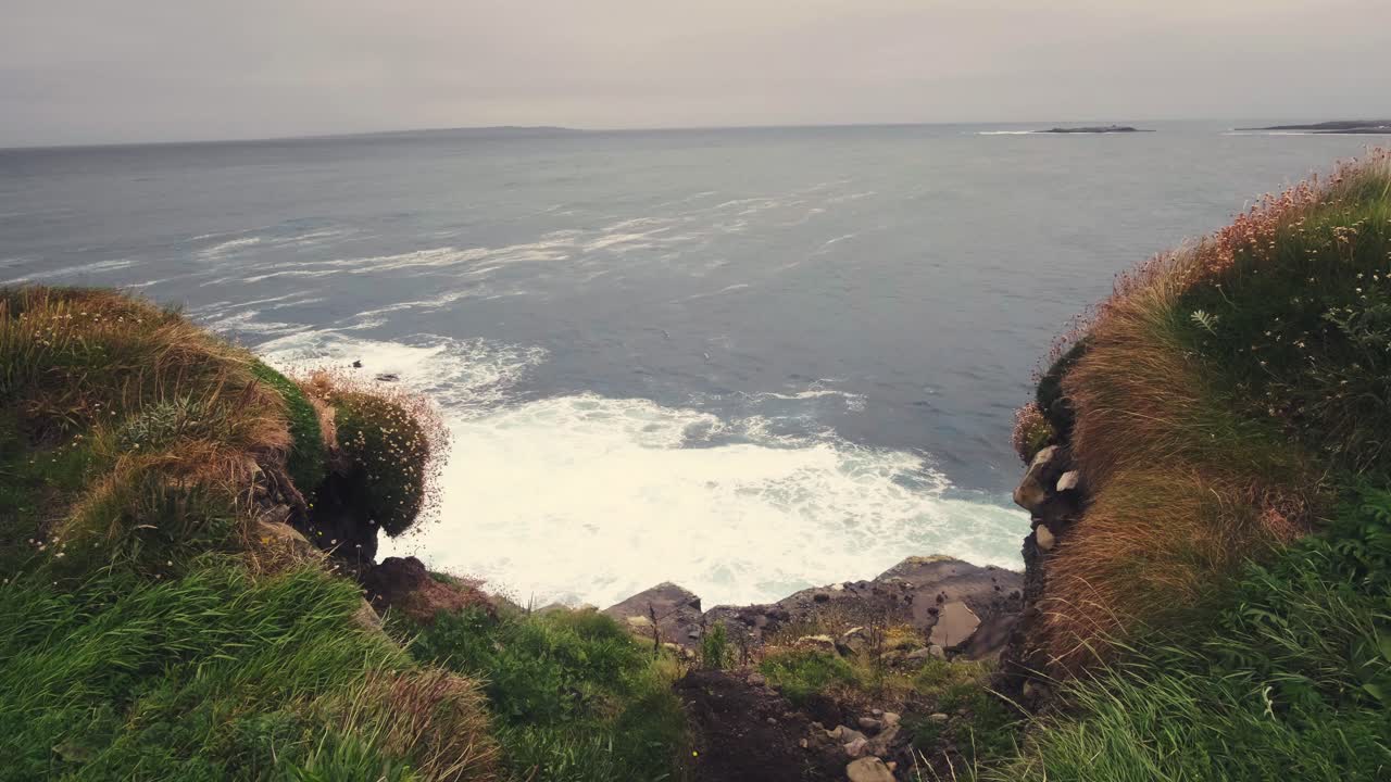 Seascape view of waves crushing on the rugged coastline near the famous Cliffs of Moher on a windy and moody day, in Ireland