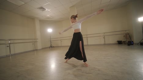 a group of young ballet students in black dancewear practicing positions in a spacious ballet studio with wooden flooring and wall-mounted barres. focused expressions and synchronized movements.