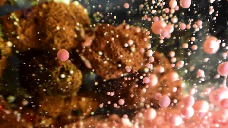 gotas de aceite en forma de gota en aumento alrededor de una estructura alienígena rocosa porosa borrosa con efecto de ralentización del tiempo 60fps