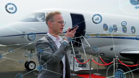 animación de una red de iconos digitales sobre un hombre de negocios caucásico hablando con un teléfono inteligente en el aeropuerto