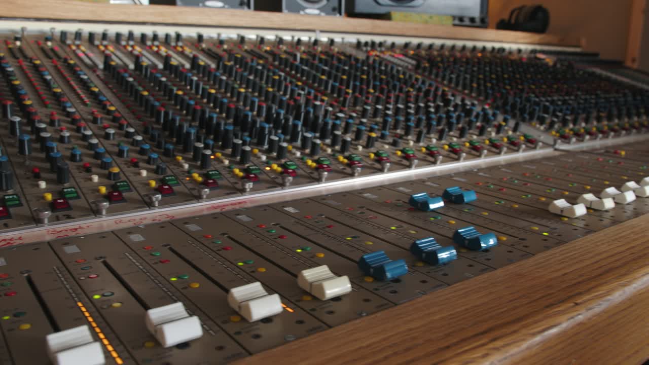 Slider shot of a music producer pushing the dials on a studio mixing console