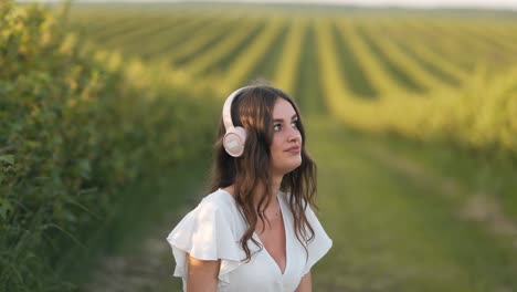 beautiful young woman sitting in a field listening to music on headphones