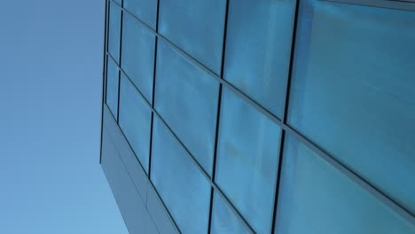 low angle view of blue reflective skyscraper facade against a clear sky