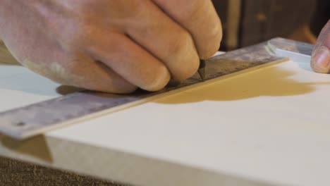 Senior-carpenter-hands-measure-a-wood-with-a-ruler-in-workshop.