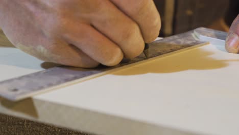 senior carpenter hands measure a wood with a ruler in workshop.