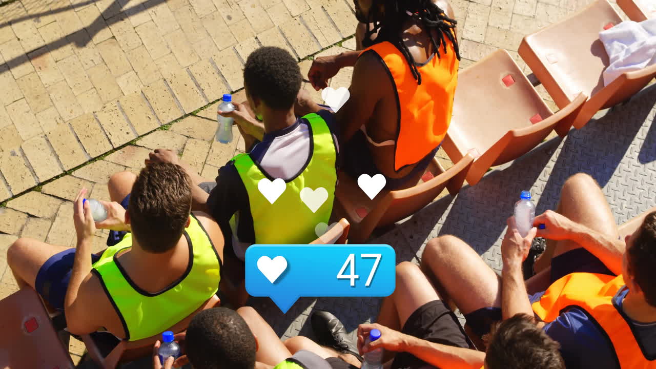 Sitting with water bottles, people in sports vests viewing animation in school