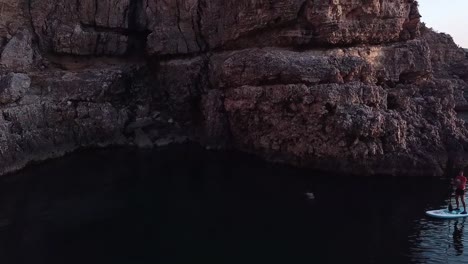 drone pan shot of guy doing paddle surf in ibiza in the sunset