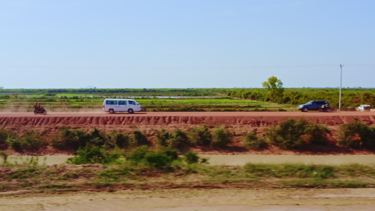 Local traffic traveling along a red mud dike roadway near Kampong Cambodia, aerial track