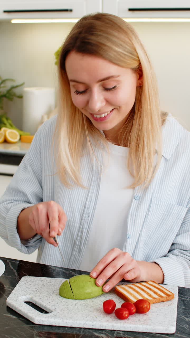 Young woman slicing avocado for tomato toast breakfast preparing healthy meal in modern home kitchen
