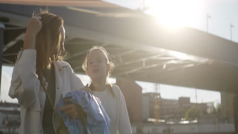 mother and daughter outdoors under a bridge