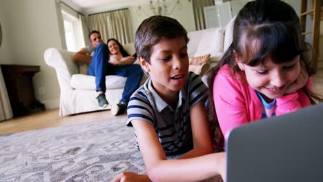 hermanos usando computadora portátil en la sala de estar