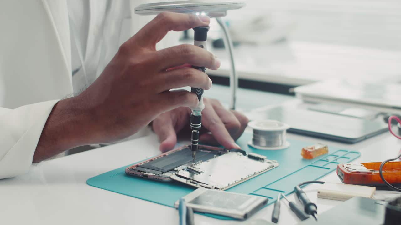 Hands of Engineer Unscrewing Detail with Screwdriver