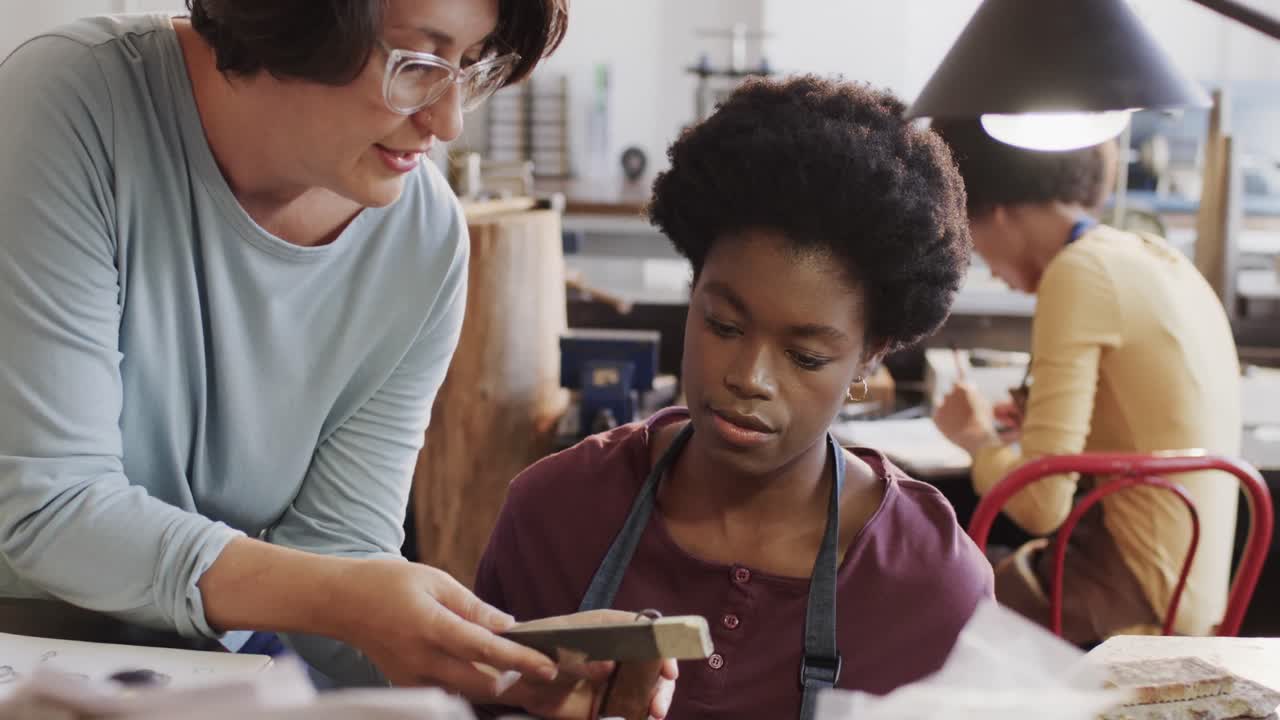 Busy diverse female workers shaping ring with handcraft tools in studio in slow motion