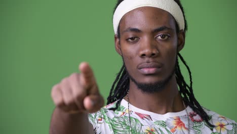 young handsome african man with dreadlocks against green background