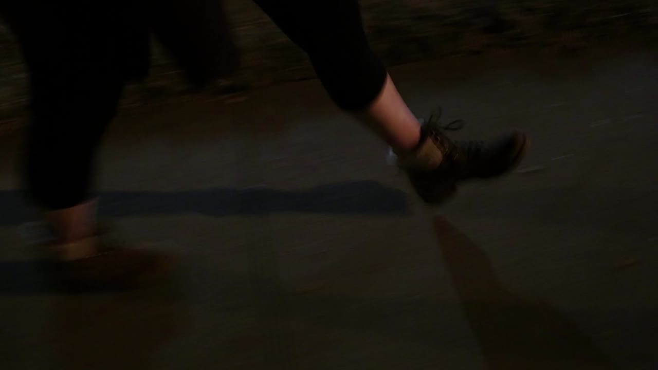 Feet of women wearing leggings waking along sidewalk high angle close up