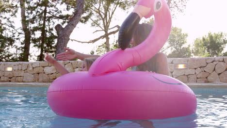 family having fun on inflatables in outdoor swimming pool