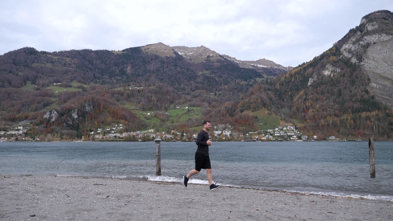 산속 호수 기슭에 있는 젊은 남자가 피트니스 앱을 실행하고 달리기 운동을 시작합니다.