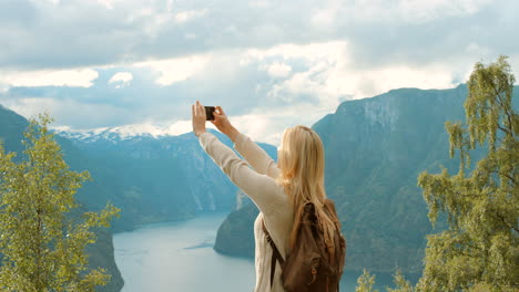 frau macht bilder von einem norwegischen fjord