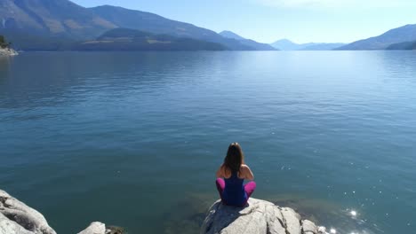 mujer realizando yoga en la orilla del lago 4k