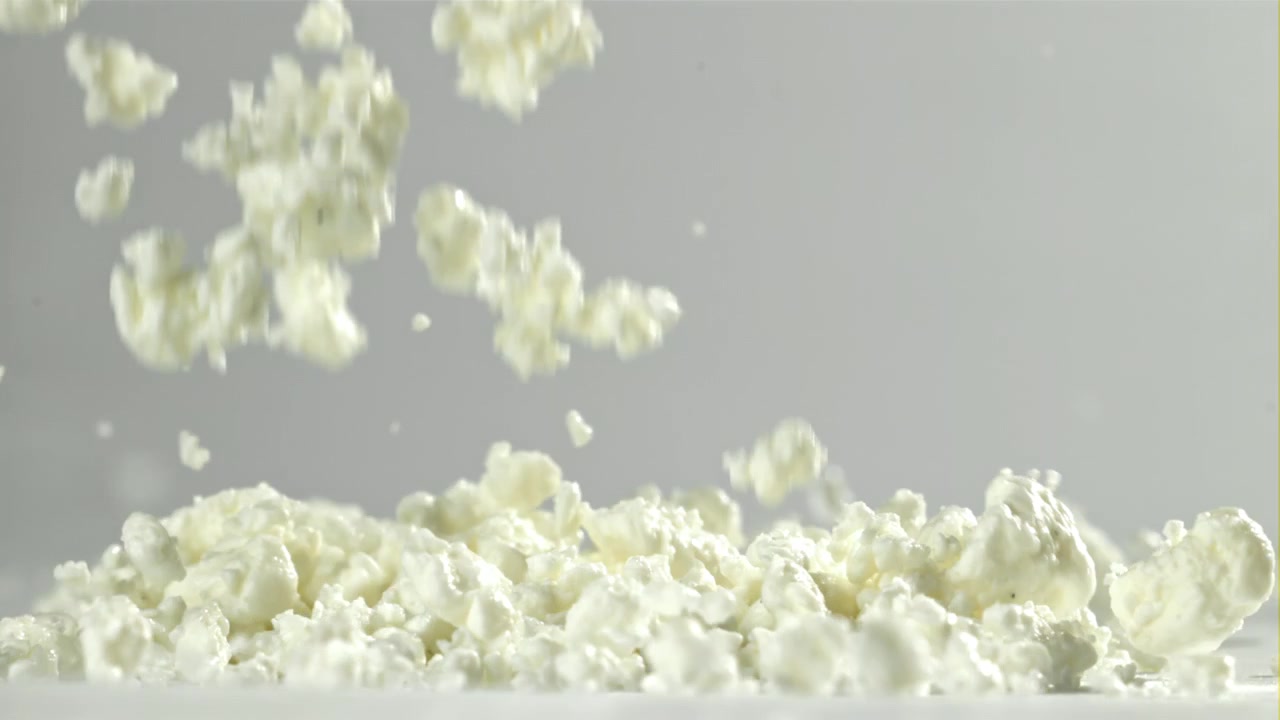 Frisk hytteost, der falder i slowmotion på hvid baggrund