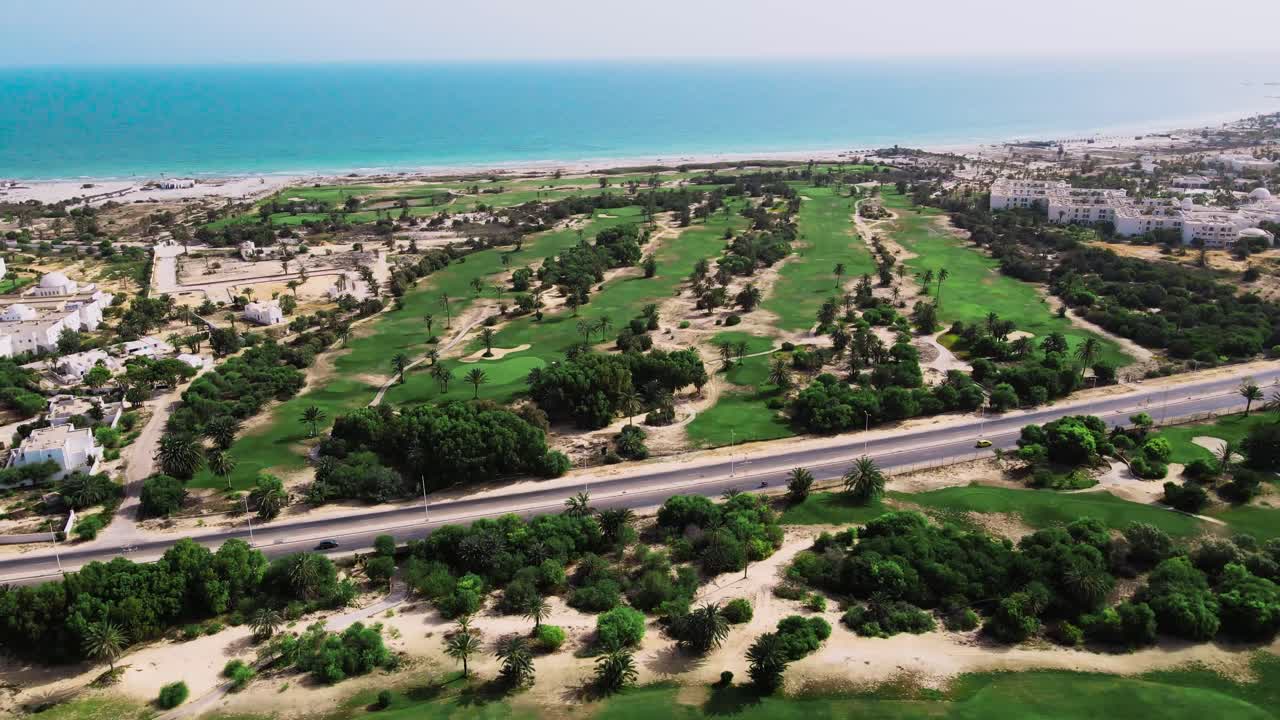 una vista aérea de un campo de golf al lado de una playa con muchos árboles y hierba verde desde arriba en túnez djerba