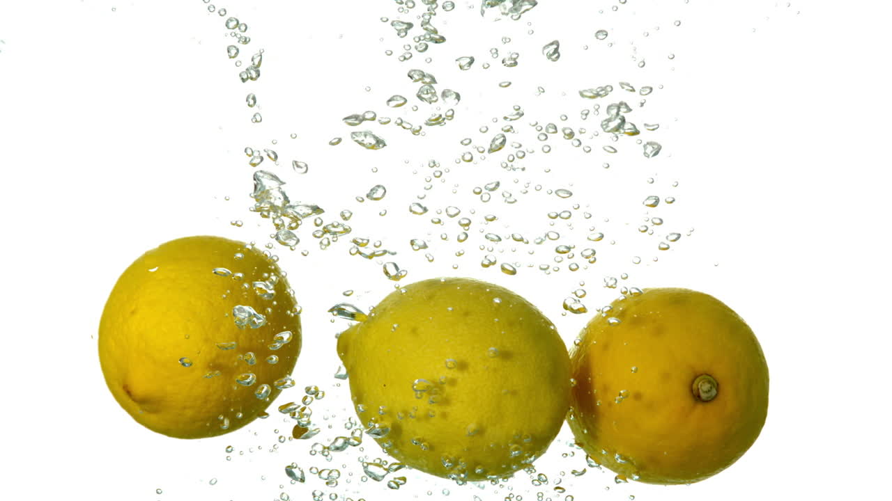 limones sumergiéndose en el agua sobre un fondo blanco