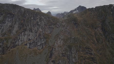 Vista-Aérea-De-Una-Pared-De-Montaña-Que-Se-Eleva,-Revelando-Picos-Alpinos,-En-Lofoten-Nublado,-Noruega---Ascendente,-Disparo-De-Drones