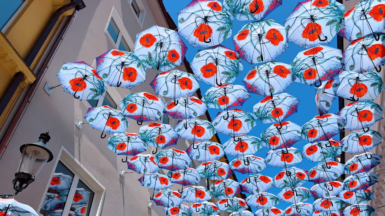 Bratislava, Slovakia, 2 June 2025: Multiple umbrellas with poppy flowers hanging above the street. Walking by the old town in Bratislava, Slovakia