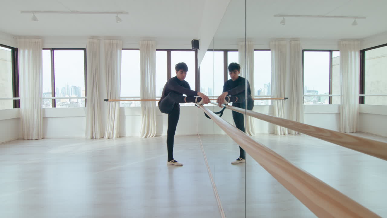 Danseur Stretching Leg at the Barre in Ballet Studio