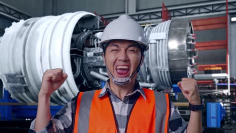 close up of asian male engineer with safety helmet screaming goal celebrating working with airplane engine maintenance conducted, analytics checking the turbine