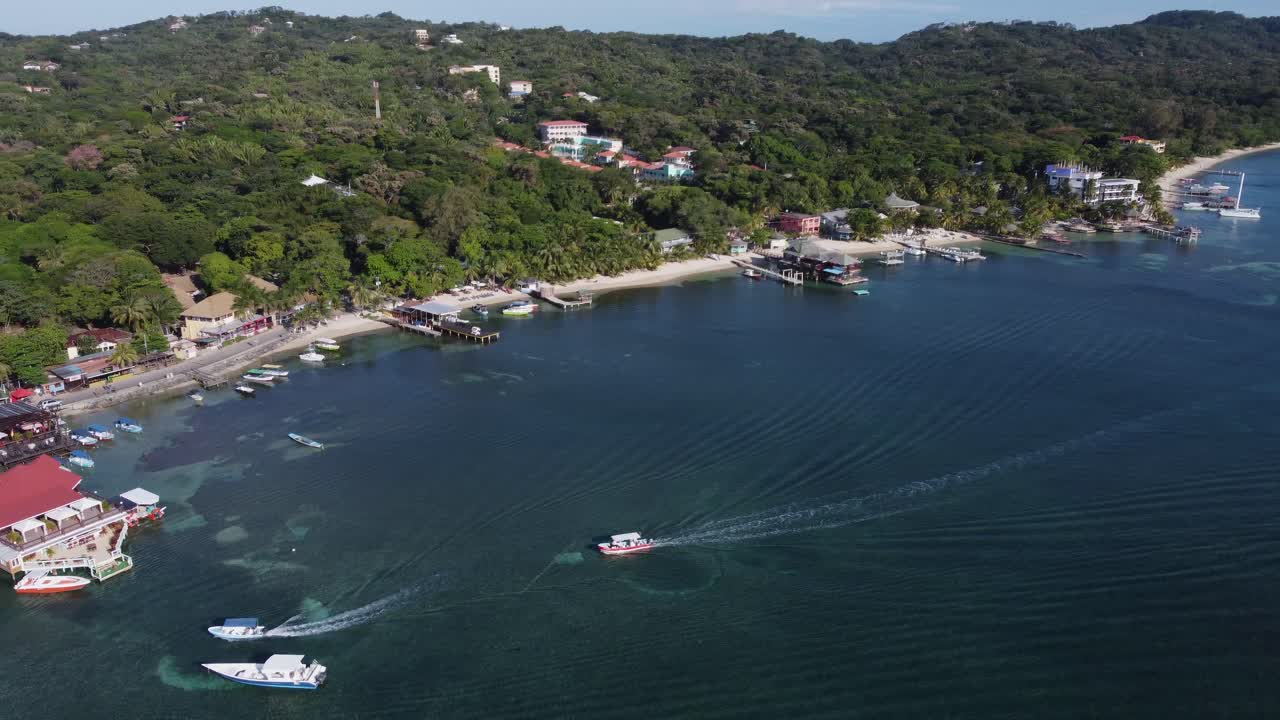 Aérea giratória: Barcos turísticos retornam ao cais, costa caribenha de Roatán.