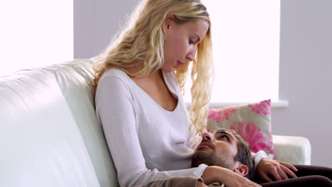 happy man lying on the couch with head on girlfriends lap