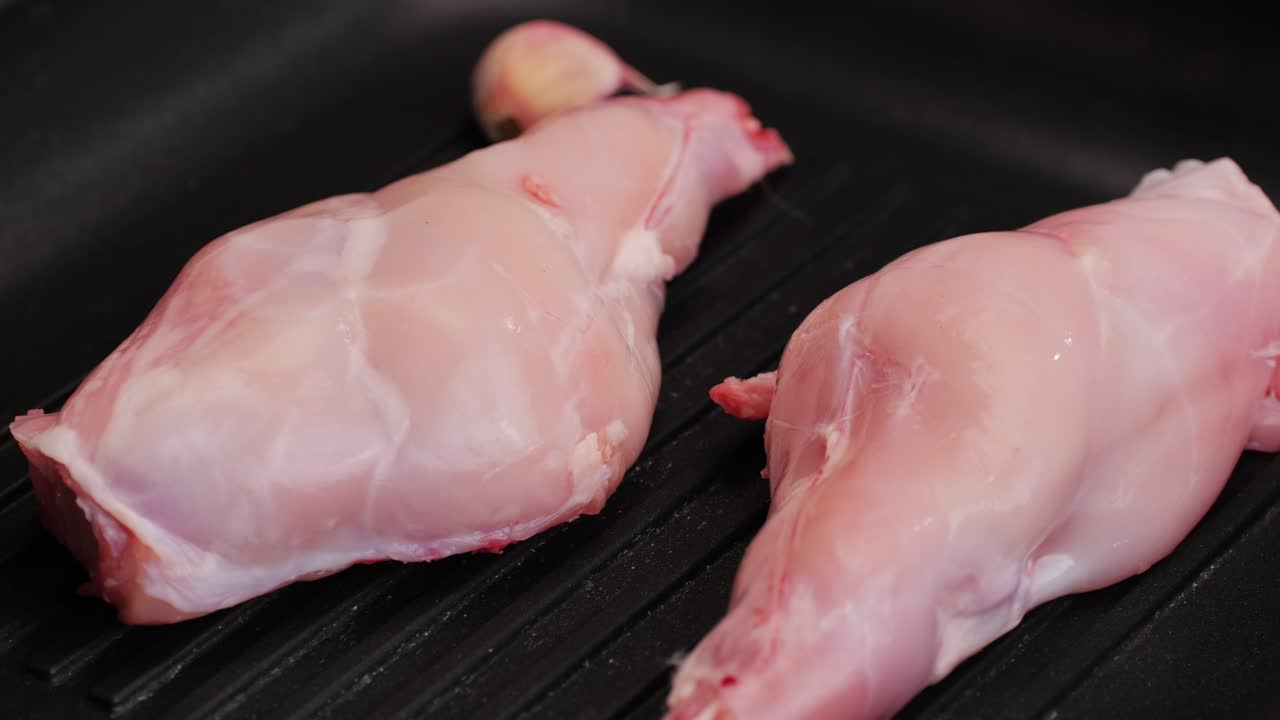 Roasted rabbit legs in a grill pan, healthy diet meat close up, chef cooking rabbit on kitchen restaurant, Black background. Top view
