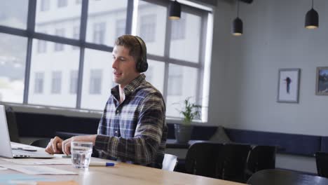 Caucasian-casual-businessman-making-video-call-using-laptop-at-desk,-slow-motion