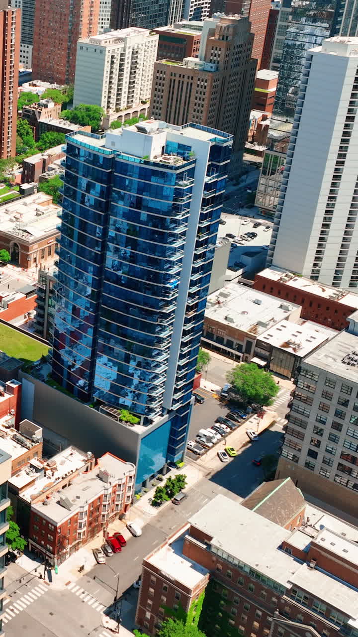 Modern tall glass buildings in downtown Chicago. Beautiful blue skyscraper with reflections. Sunny day. Aerial view. Vertical video